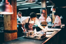 restaurant employee cook placing food on plate in kitchen