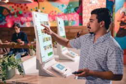 customer placing an order on a POS kiosk at a quick service restaurant