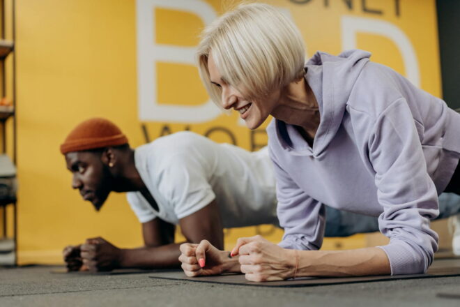 Man and woman doing arm planks in a gym