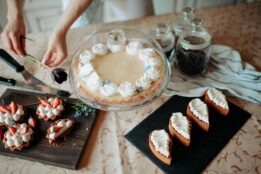 Baker arranges a flower, pie, and baked goods on a kitchen countertop