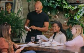 waiter at restaurant taking order and splitting check from three women sitting at table