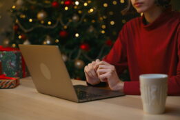 Woman shopping online while sitting at a table in front of a Christmas tree